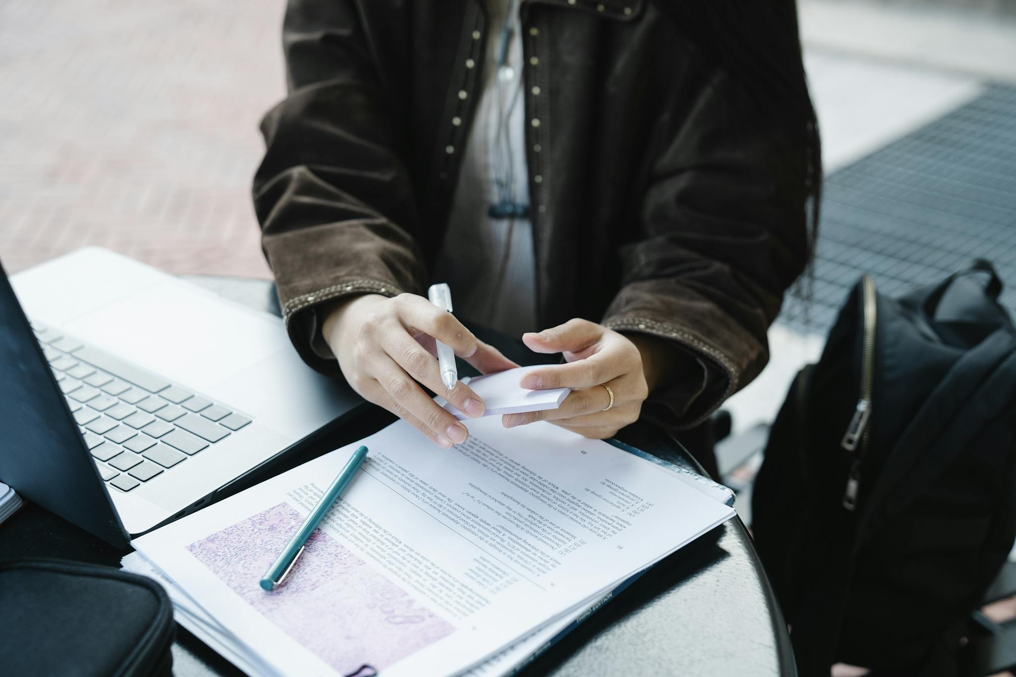 An adult engaged with a laptop and documents outside, highlighting productivity and focus.