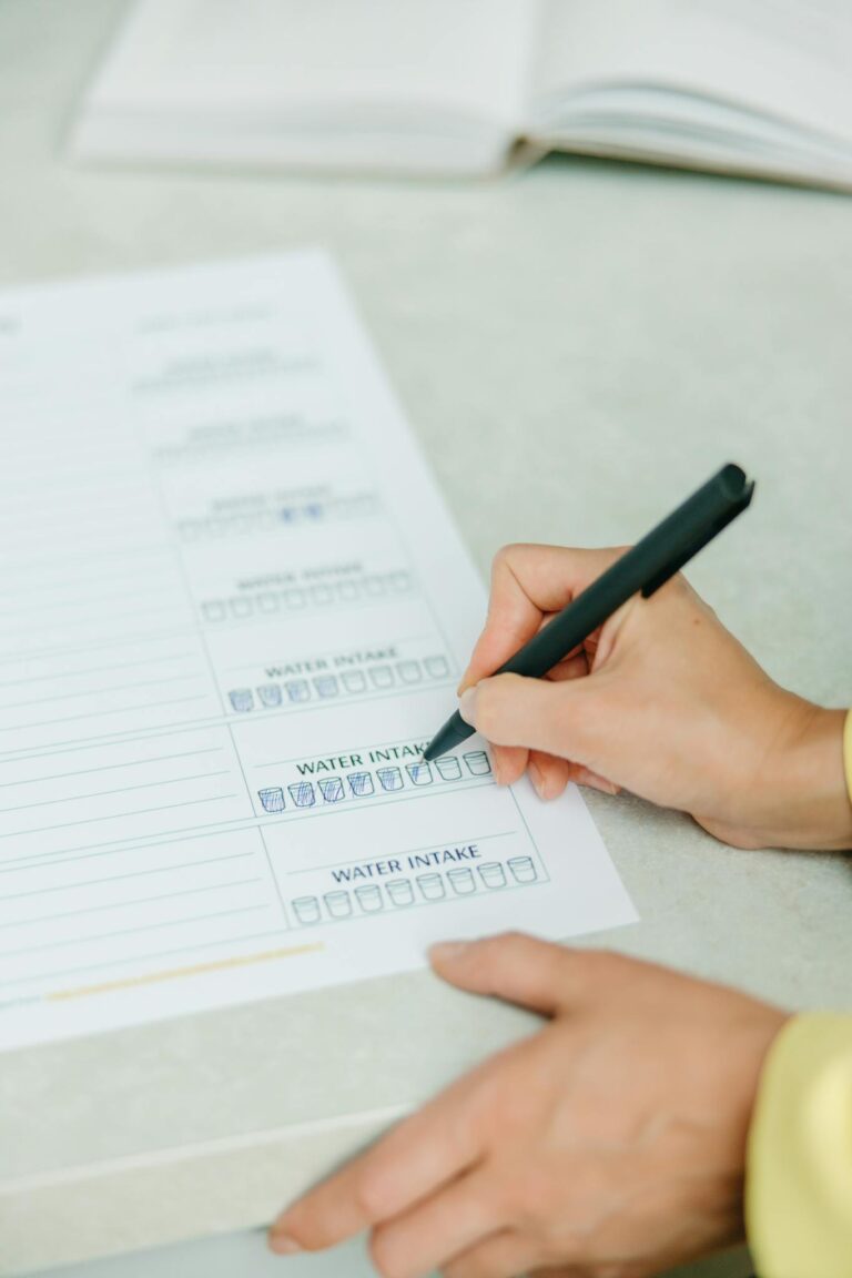 Hands filling out a nutrition plan with a focus on water intake. Ideal for health and wellness themes.