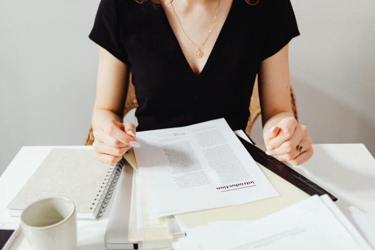 Woman sitting at a desk reviewing documents, featuring a casual work environment.